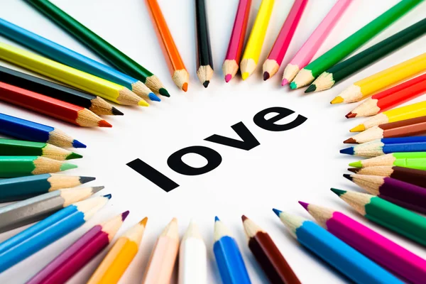 Many colored pencils arranged in circle on the word love — Stock Photo, Image
