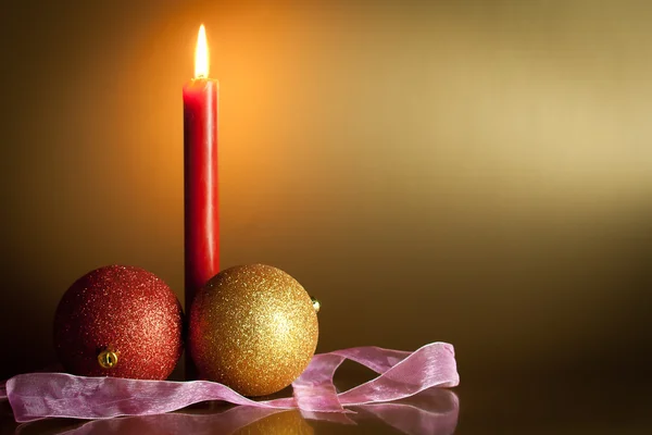 Christmas balls with red candle in background — Stock Photo, Image