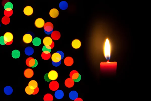 Červená svíčka s rozostřeného barevnými světly — Stock fotografie