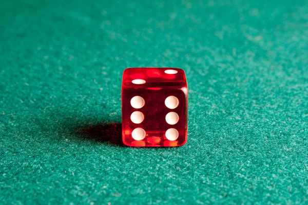 Detail of one red dice on green table — Stock Photo, Image