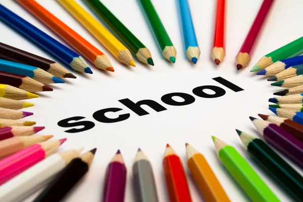 Muchos lápices de colores dispuestos en círculo en la palabra escuela — Foto de Stock