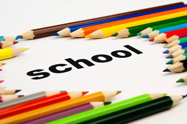 Muchos lápices de colores dispuestos alrededor de la palabra escuela — Foto de Stock