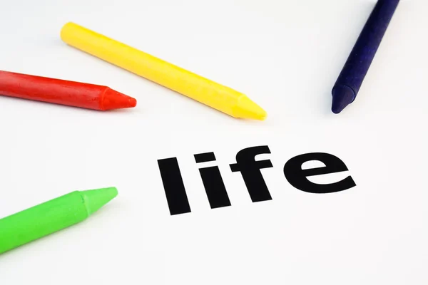 Colored wax crayons arranged on the word life