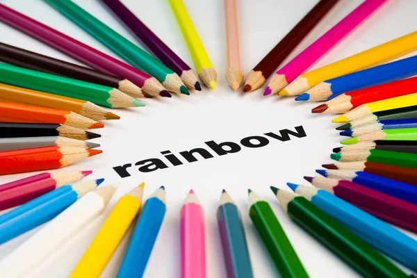 Muchos lápices de colores dispuestos en círculo en la palabra arco iris —  Fotos de Stock