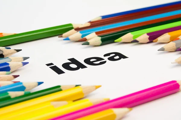 Many colored pencils arranged around the word idea — Stock Photo, Image