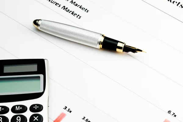 Калькулятор и ручка на финансовом графике — стоковое фото