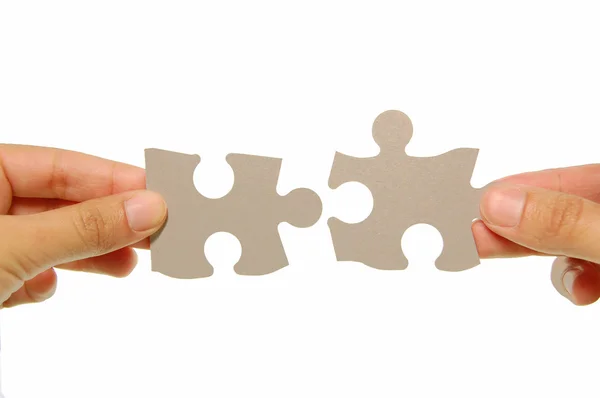 Mani che uniscono due pezzi di puzzle insieme — Foto Stock