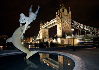gece Londra'da Dolphin heykeli ve tower bridge.