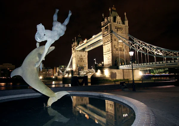Delfinstatue und Tower Bridge, bei Nacht in London. — Stockfoto