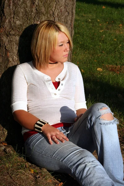 Blonďatá žena sedí na zemi v slunci strom — Stock fotografie