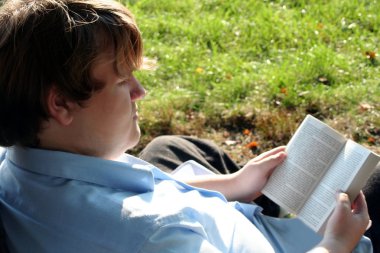 Teen Engrossed In Book Outdoors clipart