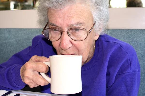 Старшая женщина потягивает кофе — стоковое фото
