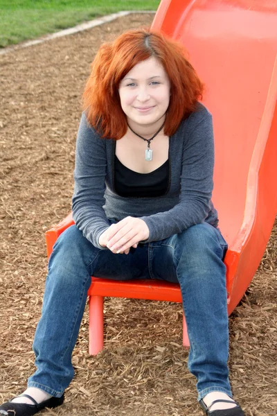 Sonriente adolescente sentado en el tablero deslizante — Foto de Stock