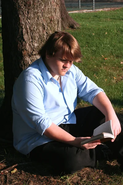 Мальчик-подросток читает в парке — стоковое фото