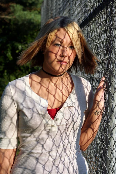 Giovane donna bionda coperta da ombre recinzione — Foto Stock