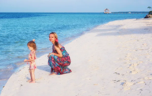 Een jonge moeder en een dochter op het strand — Stockfoto