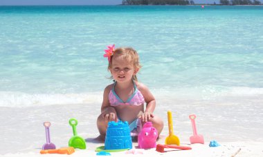 A baby girl is playing on the beach clipart