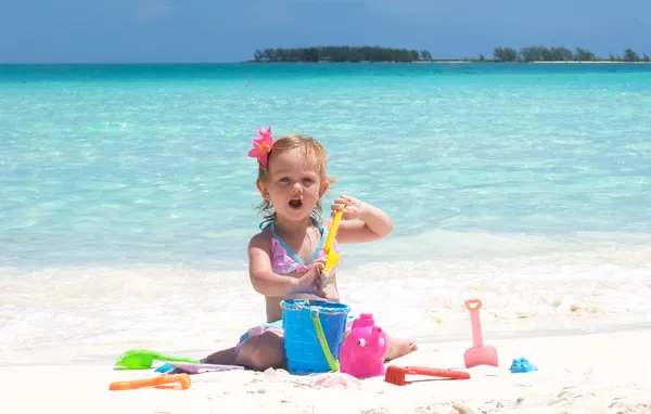 Una bambina sta giocando con i suoi giocattoli sulla spiaggia — Foto Stock