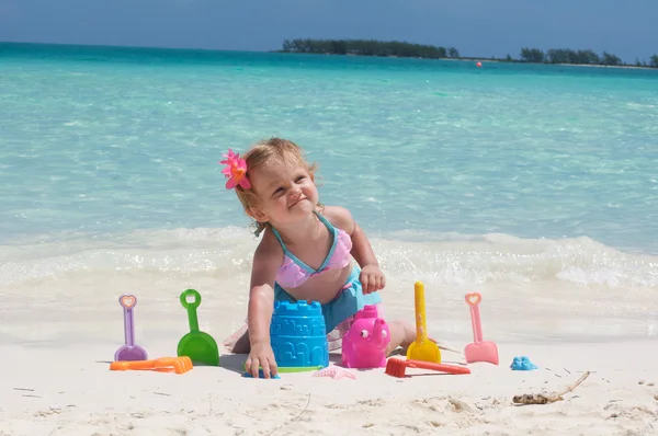 Uma menina está brincando com seus brinquedos na praia Imagens Royalty-Free