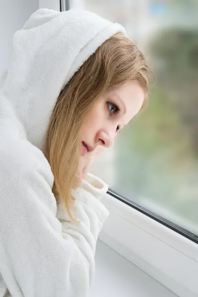 Красивая молодая девушка грустит у окна — стоковое фото
