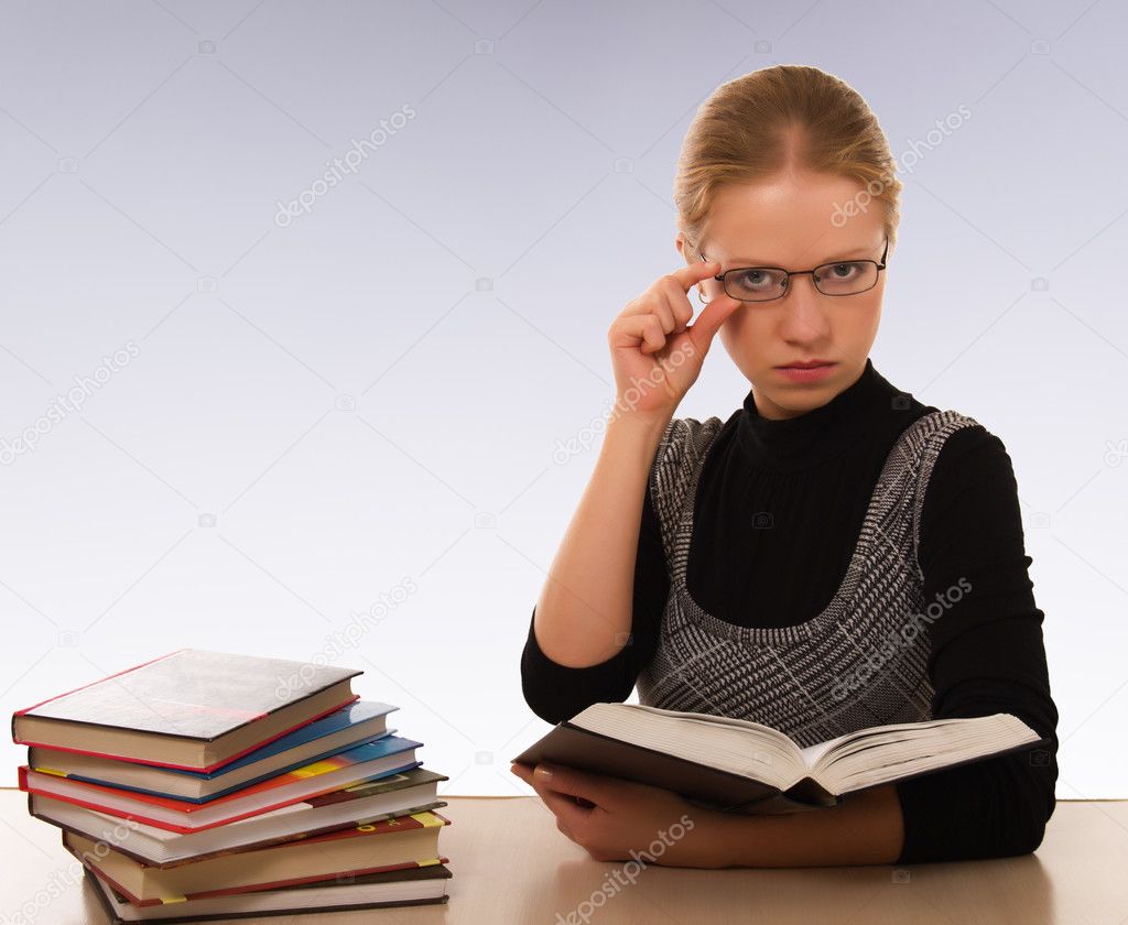 Strict woman with a book sitting at table