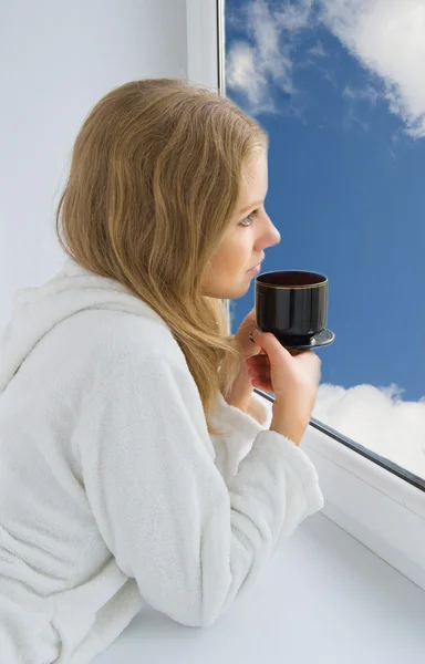 Jovem mulher bonita bebendo café pela janela — Fotografia de Stock