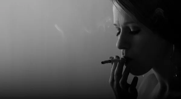 Красивая молодая женщина курит сигарету — стоковое фото