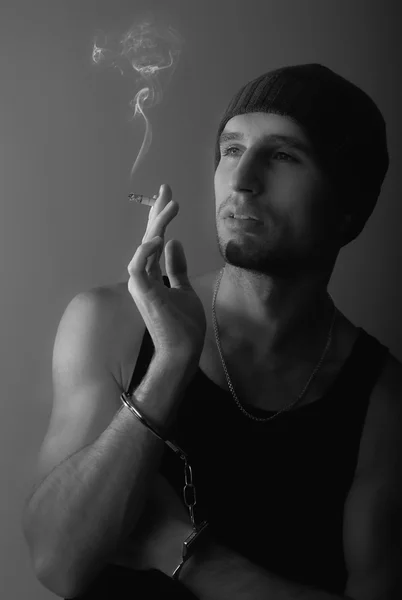 Zły człowiek w kajdankach z papierosem — Zdjęcie stockowe
