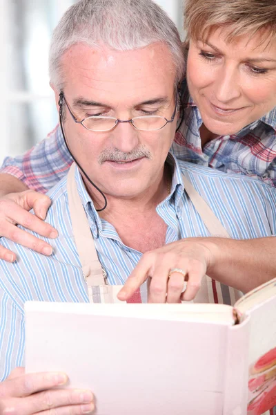 Ehepaar berät sich mit Kochbuch — Stockfoto