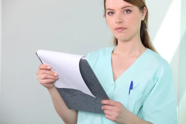 Verpleegkundige in het ziekenhuis scrubs onderzoeken een Klembord — Stockfoto