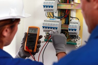 Electrician and his apprentice working on a fuse board clipart