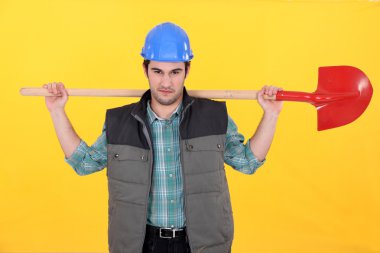 Scowling labourer carrying a shovel clipart