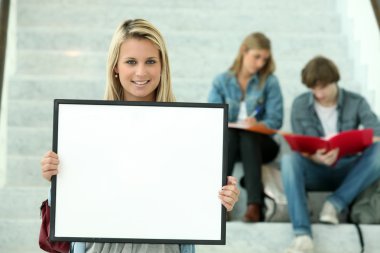 Girl holding a white board with students sitting in the background clipart