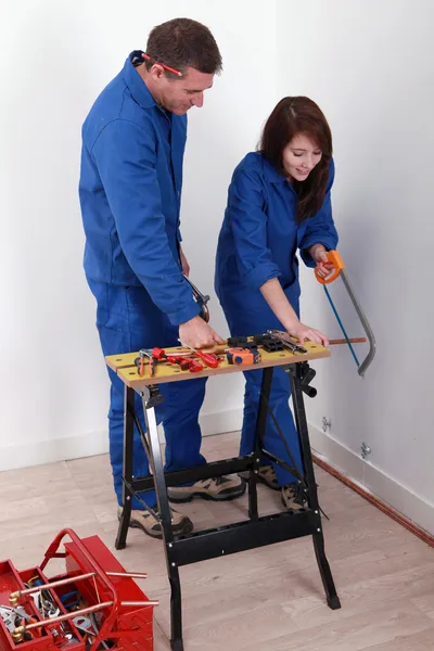 Travailleur montrant à un apprenti comment utiliser une scie à métaux — Photo