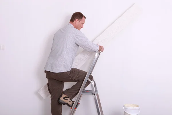 Muž šplhací žebřík drží tapety — Stock fotografie