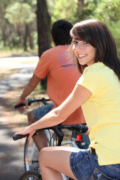 Mulher bonita e seu namorado andar de bicicleta pela floresta — Fotografia de Stock