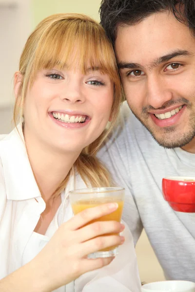 Νεαρό ζευγάρι πίνοντας χυμό πορτοκάλι και καφέ — Φωτογραφία Αρχείου