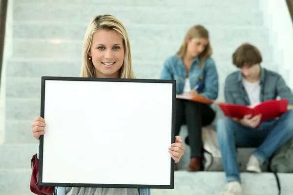 stock image Girl holding a white board with students sitting in the background