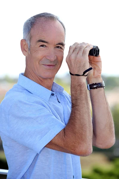 Older man with a pair of binoculars — Stock Photo, Image