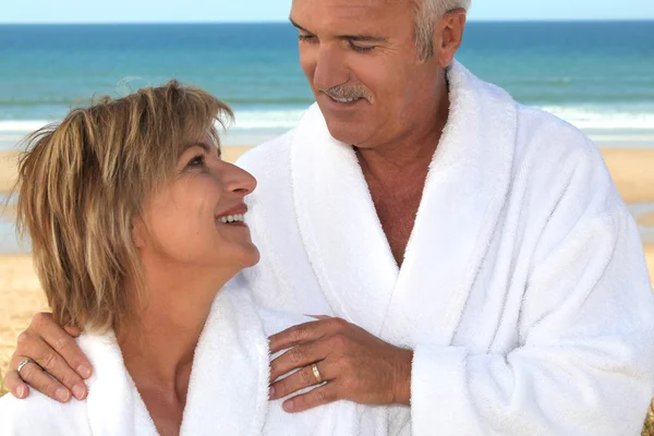Casal usando um roupão de banho em uma praia . — Fotografia de Stock