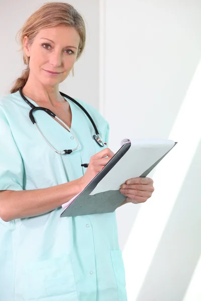 Sjuksköterska skriva på clip-board — Stockfoto