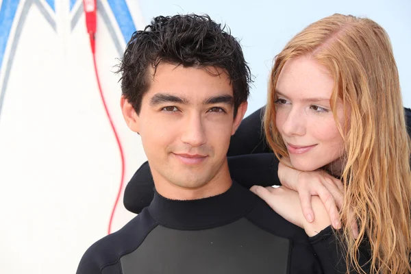 Young surfing couple in wetsuits — Stock Photo, Image