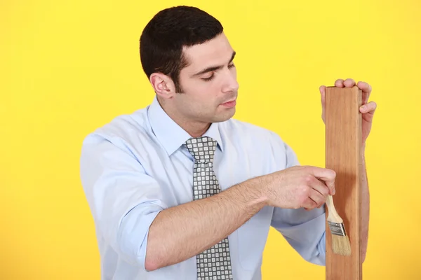 Man applying varnish to a wooden plank — Stock Photo, Image