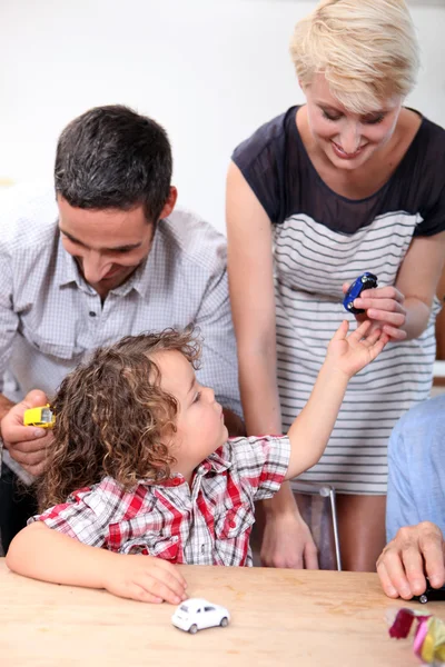 Familj spelar med en pojkes leksaksbilar — Stockfoto