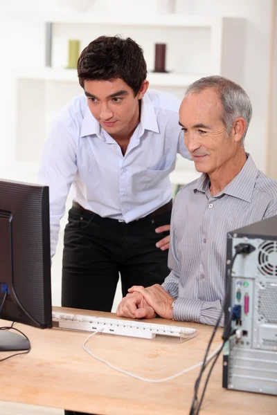 Enkel zeigt seinem Großvater, wie man einen Computer bedient — Stockfoto