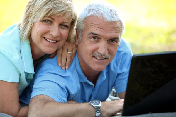 Portret uśmiechający się starsza para z laptopa na zewnątrz — Zdjęcie stockowe