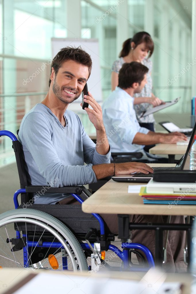 Smiling man in a wheelchair working in an office — Stock Photo