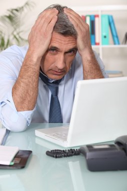 Stressed man using laptop clipart