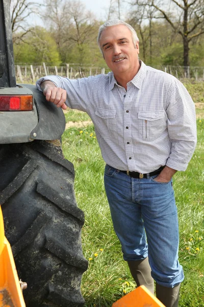 Человек, стоящий рядом с трактором — стоковое фото