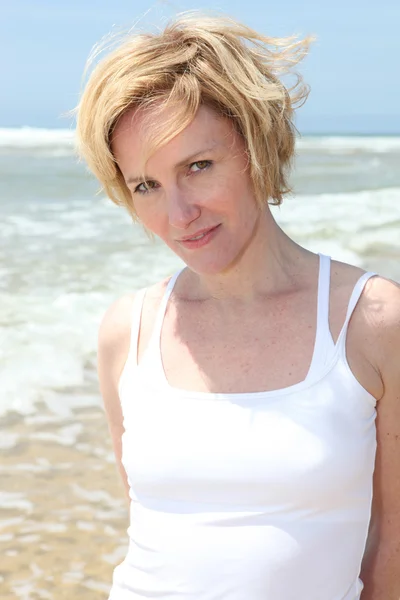 Een vrouw op een strand dat kijkt naar ons. — Stockfoto